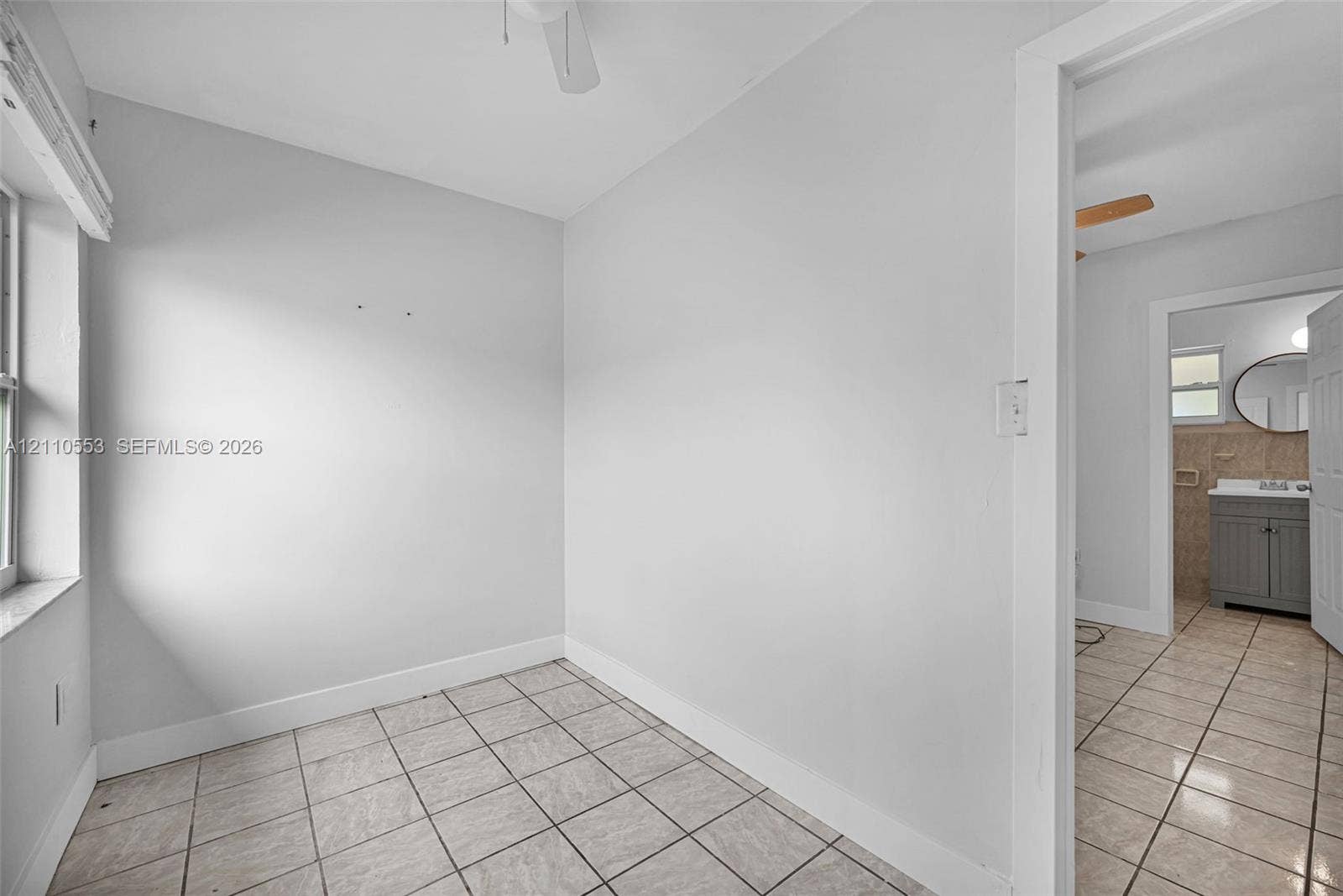 16611 SW 108th Court, Miami, FL 33157 Neutral-toned interior space featuring light-colored ceramic tile flooring, a ceiling-mounted fan, and natural light via a single window