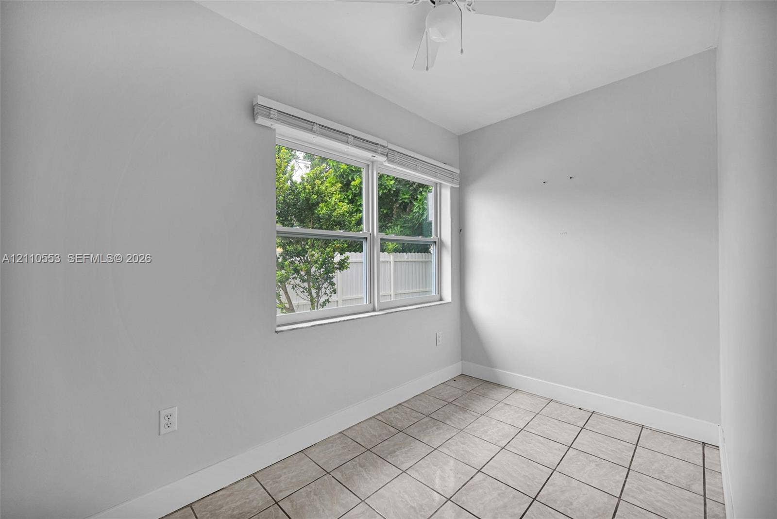 16611 SW 108th Court, Miami, FL 33157 Neutral-toned room featuring tile flooring, a dual-pane window with white blinds, and a ceiling-mounted light fixture with a fan