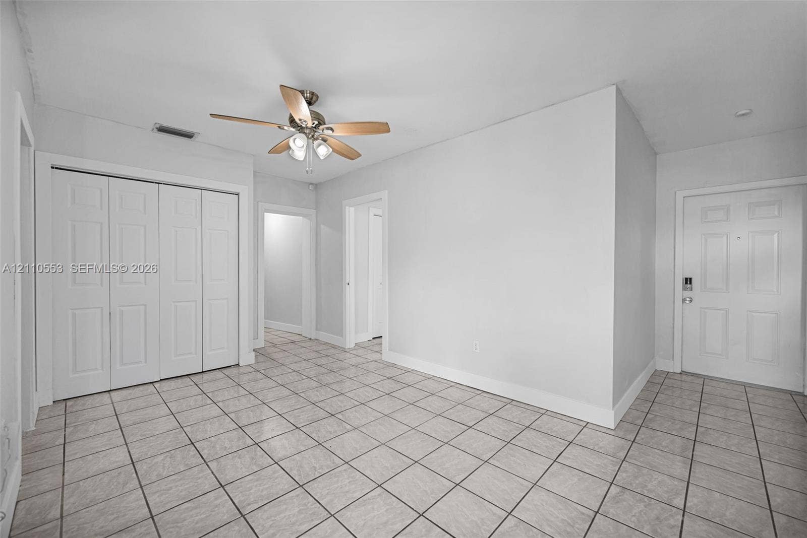 16611 SW 108th Court, Miami, FL 33157 Interior space featuring neutral wall paint, grid-pattern tile flooring, a multi-panel door, built-in closet with multi-panel doors, and a ceiling-mounted light fixture with a fan