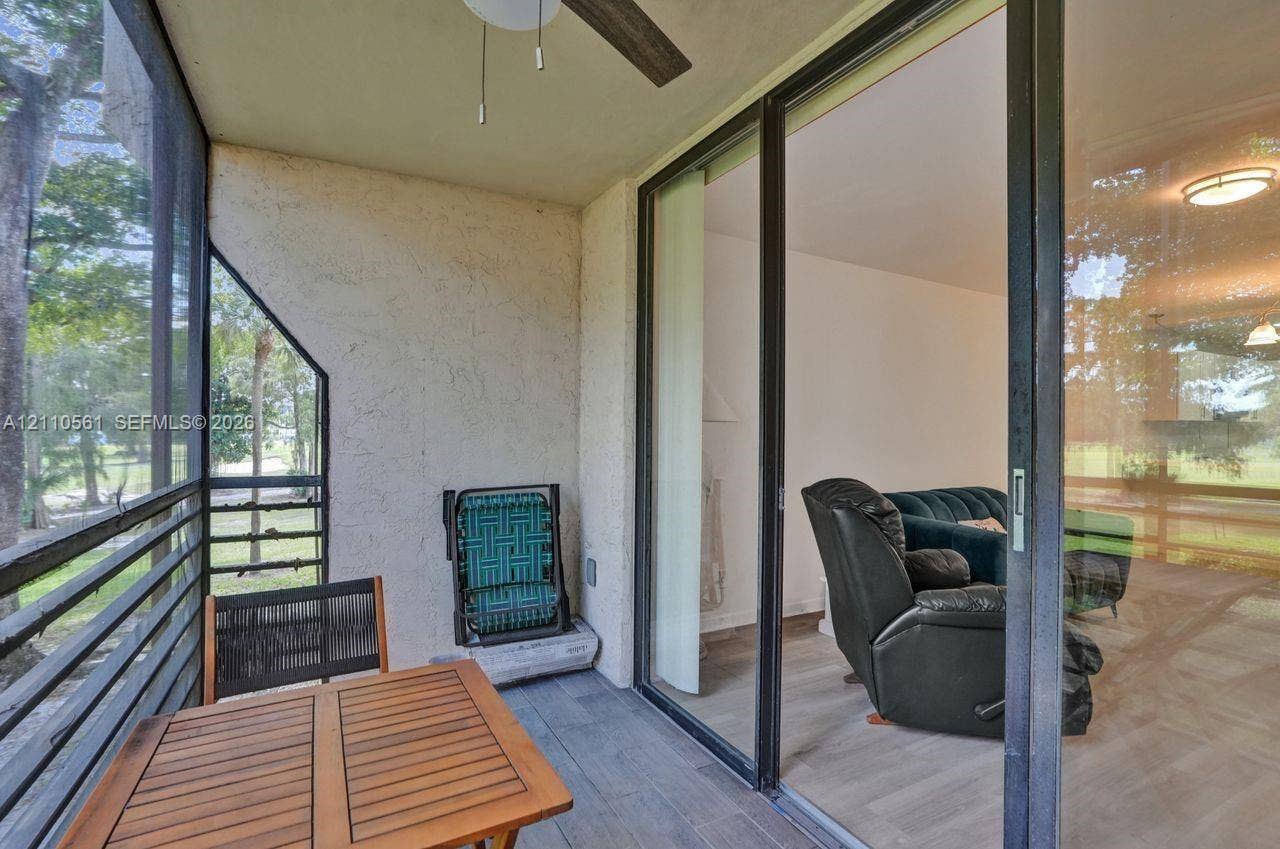 7950 W Mcnab Road, #222, Tamarac, FL 33321 Screened-in balcony featuring grey wood-finish flooring, a ceiling fan, and large sliding glass doors