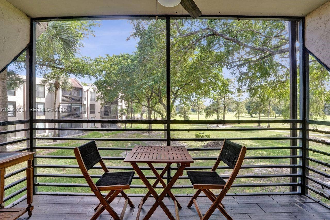 7950 W Mcnab Road, #222, Tamarac, FL 33321 Screened-in balcony featuring wood-finish tile flooring, ceiling fan, and metal railings