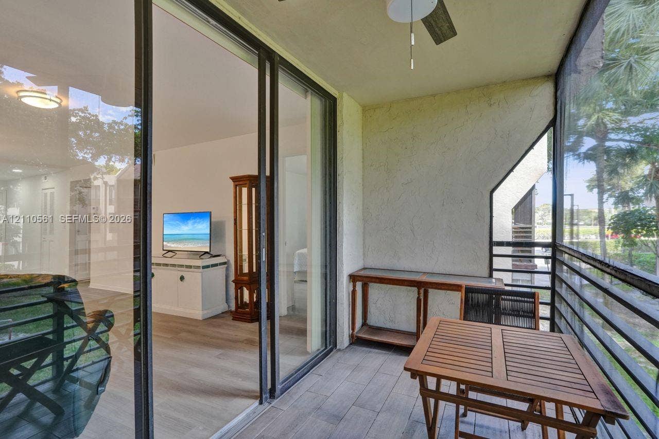 7950 W Mcnab Road, #222, Tamarac, FL 33321 Screened balcony featuring wood-finish flooring, a ceiling fan, and sliding glass door access