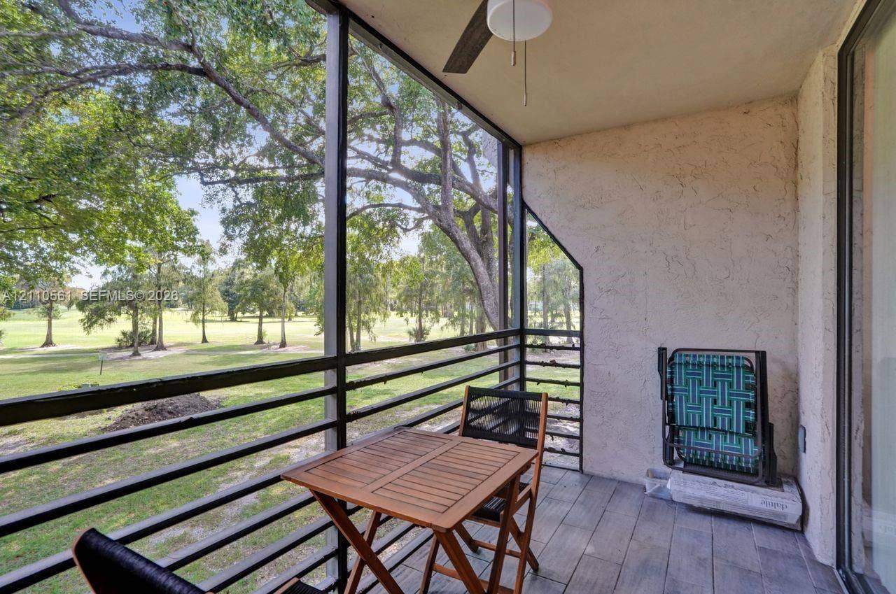 7950 W Mcnab Road, #222, Tamarac, FL 33321 Screened-in balcony featuring wood-finish flooring, metal railing, and a ceiling-mounted fan