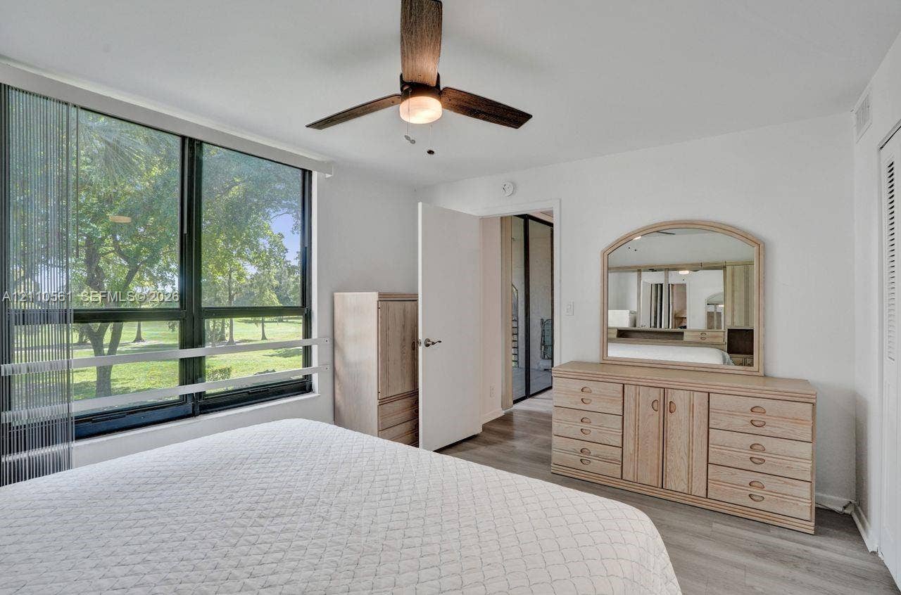 7950 W Mcnab Road, #222, Tamarac, FL 33321 Floor-to-ceiling windows, wood-finish flooring, and a ceiling fan with integrated lighting
