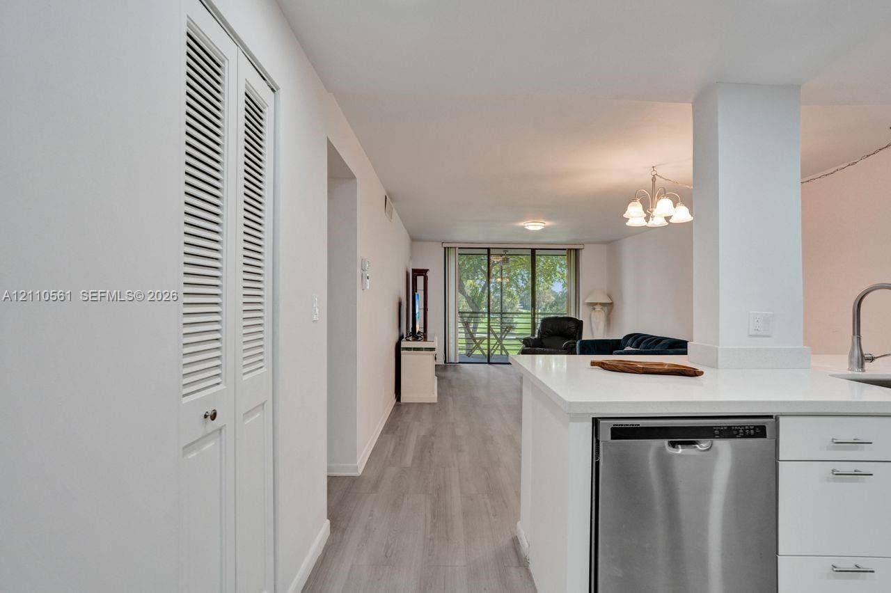 7950 W Mcnab Road, #222, Tamarac, FL 33321 Interior space featuring wood-finish flooring, white cabinetry, integrated stainless steel dishwasher, louvered-door closet, and sliding glass balcony doors
