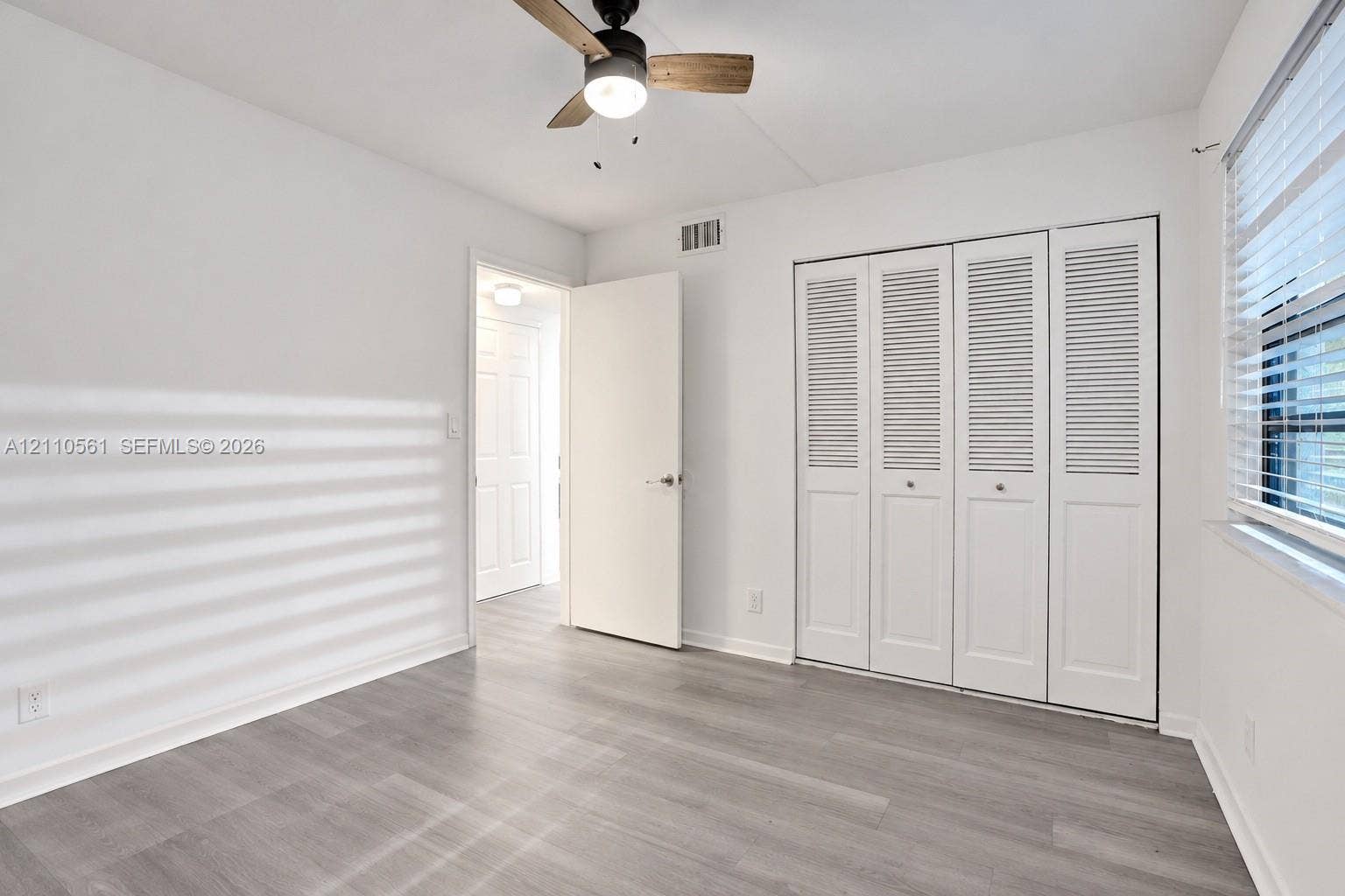 7950 W Mcnab Road, #222, Tamarac, FL 33321 Wood-finish flooring, white louvered closet doors, and a ceiling fan with integrated lighting