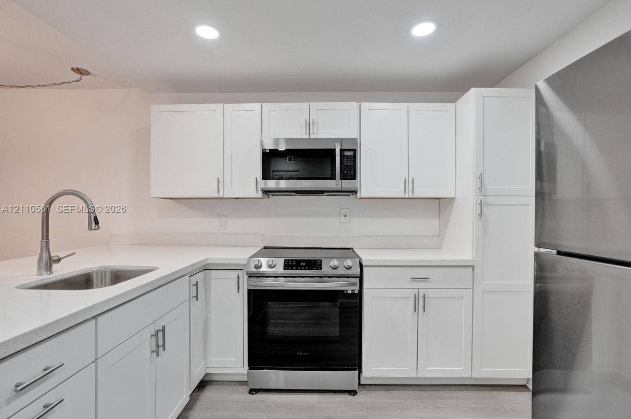 7950 W Mcnab Road, #222, Tamarac, FL 33321 Kitchen featuring white shaker-style cabinetry, quartz countertops, stainless steel appliances, a pull-down kitchen faucet, and recessed lighting