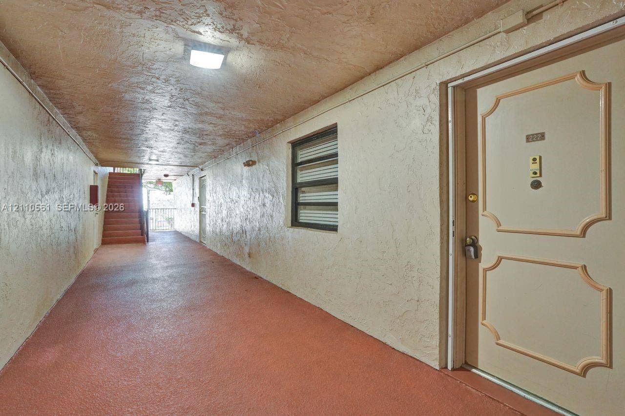 7950 W Mcnab Road, #222, Tamarac, FL 33321 Covered exterior walkway with textured ceiling, flush-mount lighting, and solid-core paneled entry door