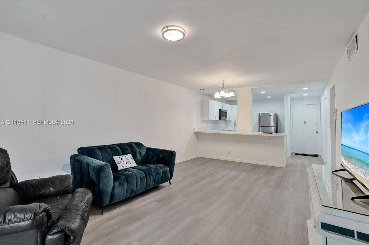 7950 W Mcnab Road, #222, Tamarac, FL 33321 Open-concept area featuring wood-finish flooring, a breakfast bar, recessed lighting, and white cabinetry