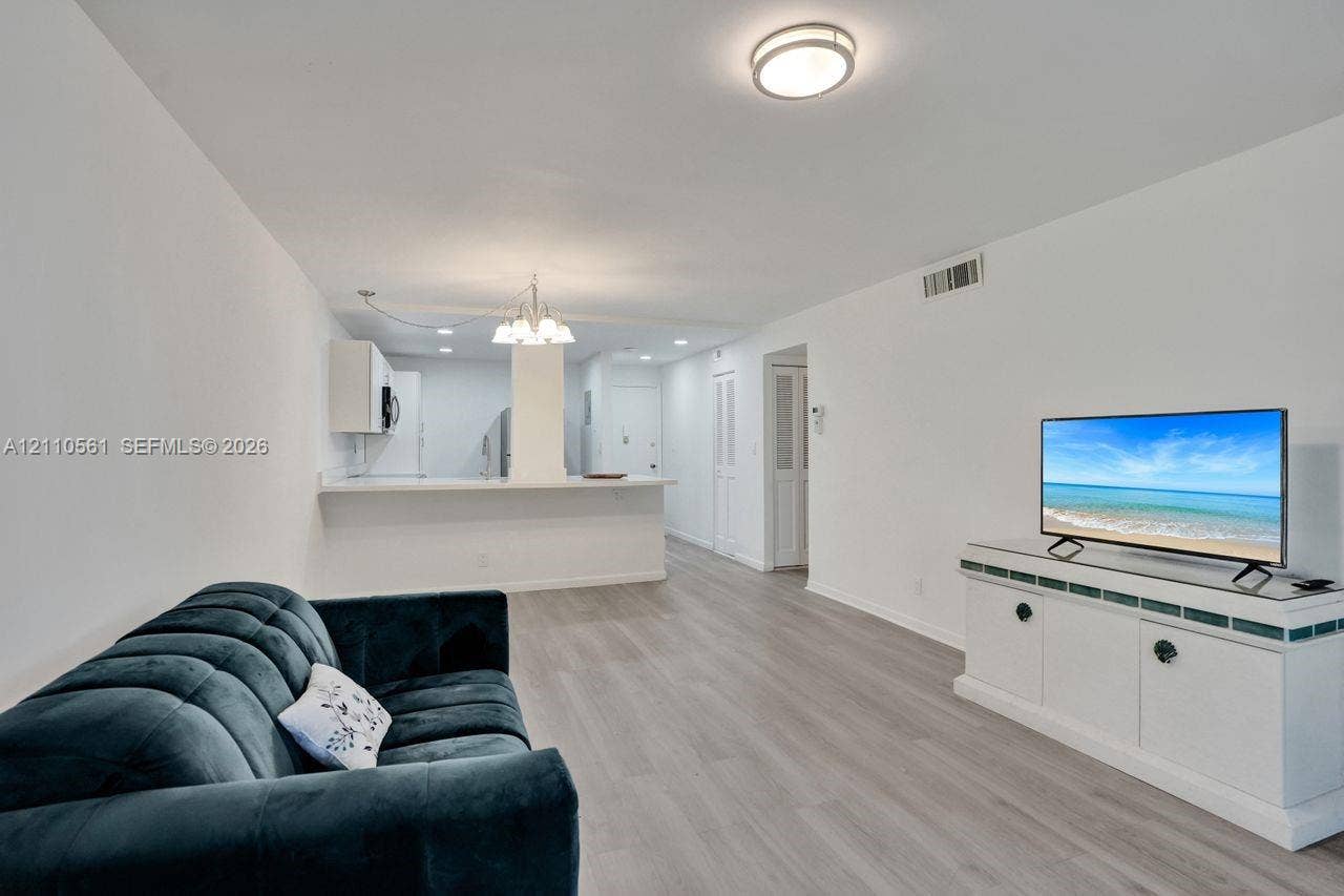 7950 W Mcnab Road, #222, Tamarac, FL 33321 Open-concept floor plan featuring wood-finish flooring, a breakfast bar, recessed lighting, and a decorative chandelier
