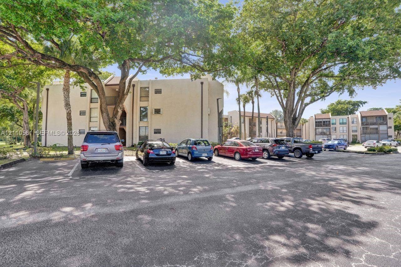 7950 W Mcnab Road, #222, Tamarac, FL 33321 Multi-story stucco exterior buildings featuring paved surface parking and mature canopy trees