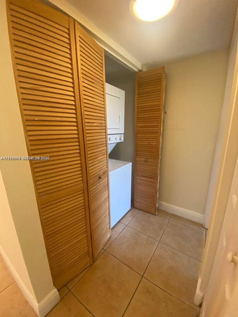 Laundry space featuring tile flooring and bi-fold wood louvred closet doors