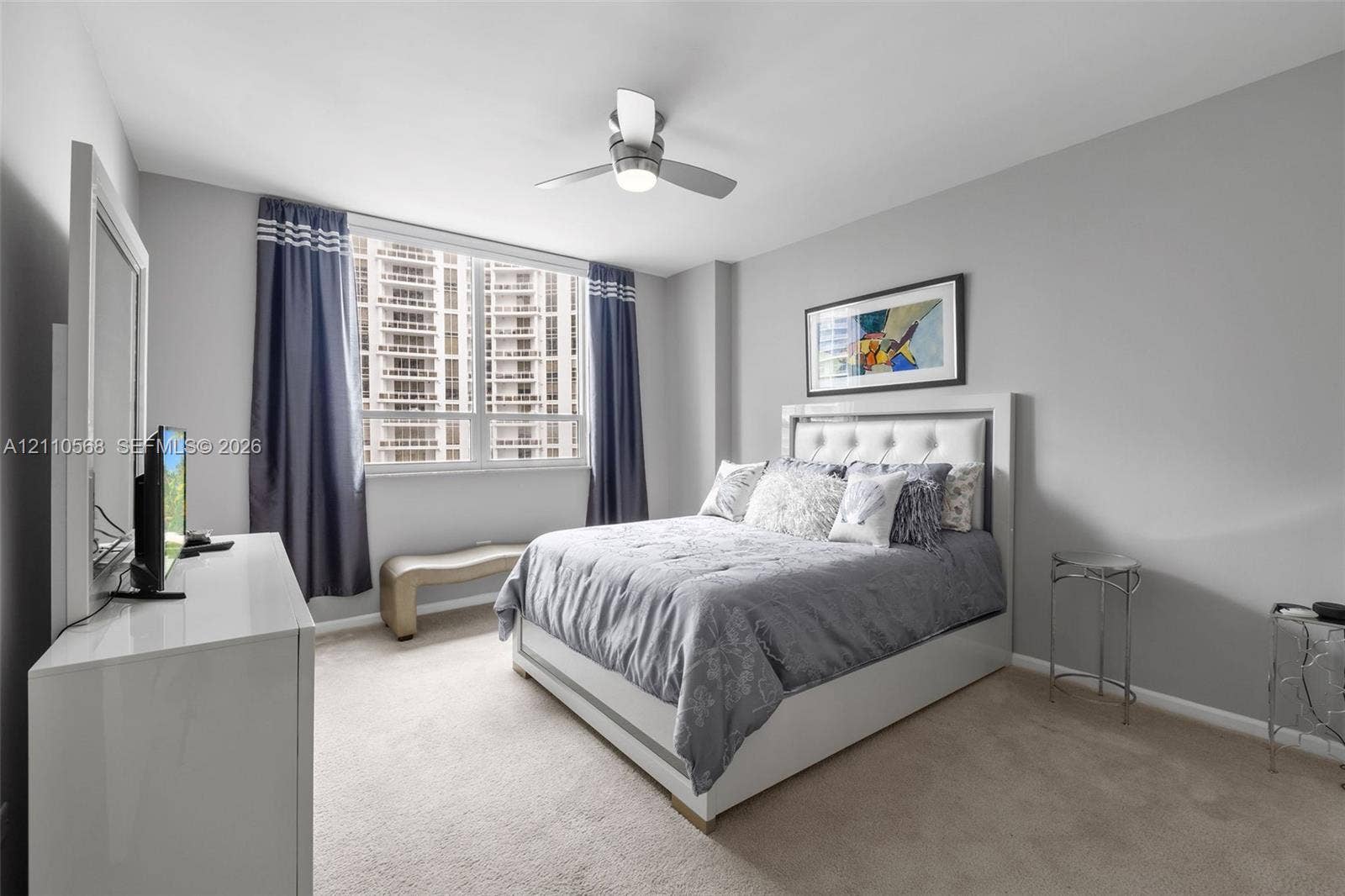801 Brickell Key Boulevard, #2006, Miami, FL 33131 Neutral-toned bedroom featuring wall-to-wall carpeting, large windows, and a ceiling-mounted light fixture with fan
