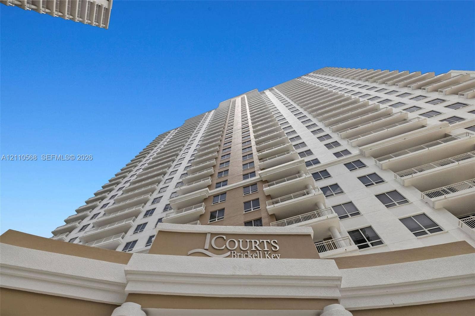 801 Brickell Key Boulevard, #2006, Miami, FL 33131 High-rise exterior architecture featuring stacked private balconies, a multi-story neutral facade, and column-supported entryway signage