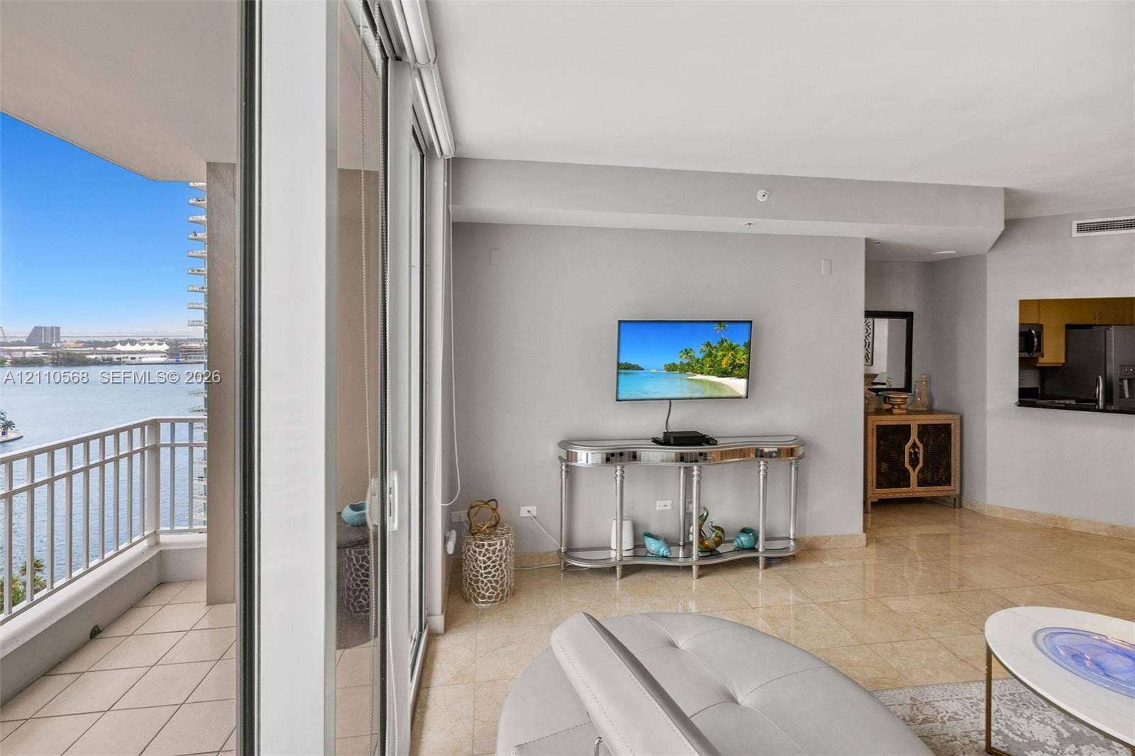 801 Brickell Key Boulevard, #2006, Miami, FL 33131 Living area featuring polished stone tile flooring, floor-to-ceiling sliding glass doors, and a tiled private balcony with metal railing overlooking the water