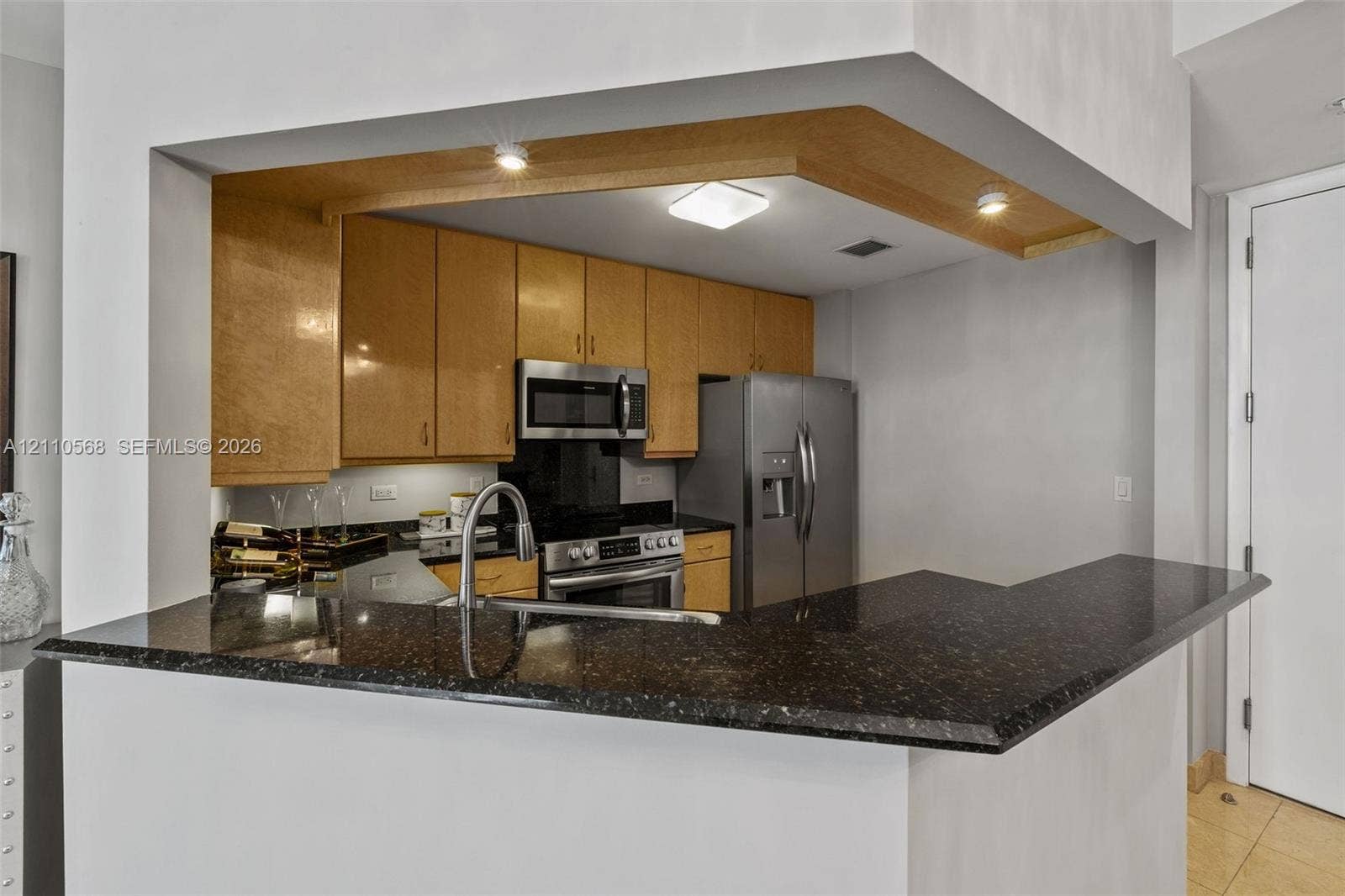 801 Brickell Key Boulevard, #2006, Miami, FL 33131 Kitchen featuring wood cabinetry, stone countertops, stainless steel appliances, a breakfast bar, and integrated recessed lighting