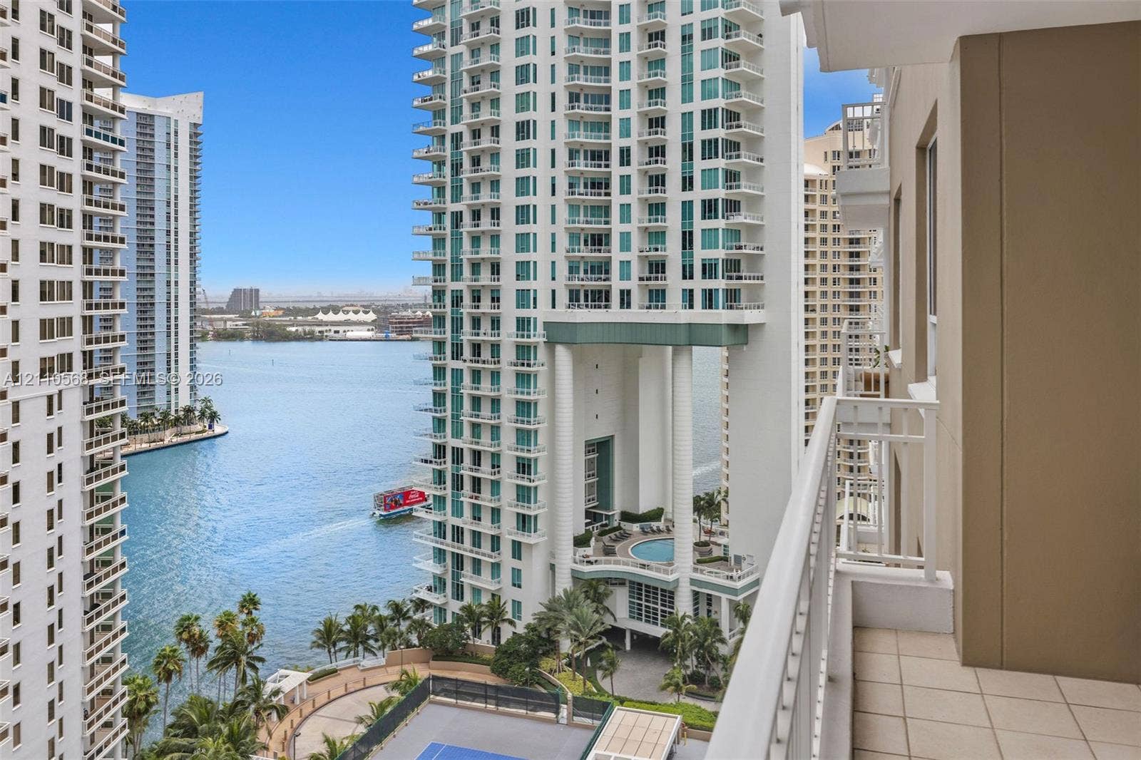 801 Brickell Key Boulevard, #2006, Miami, FL 33131 Covered balcony featuring tile flooring and a white metal railing, overlooking the water and metropolitan skyline