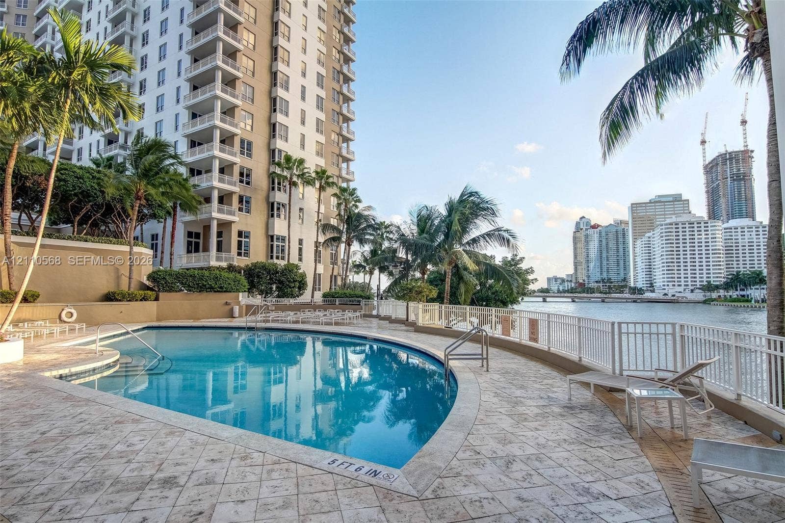 801 Brickell Key Boulevard, #2006, Miami, FL 33131 Waterfront swimming pool with a stone deck, perimeter safety fencing, and surrounding palm trees