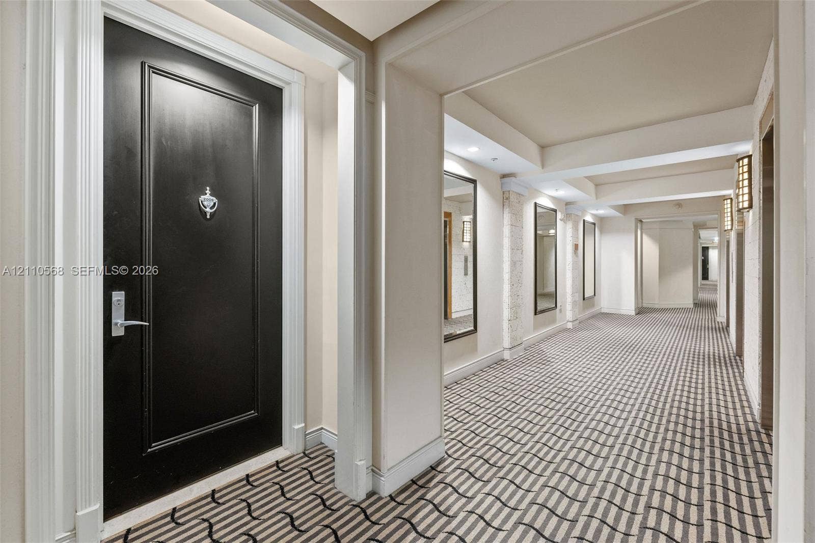 801 Brickell Key Boulevard, #2006, Miami, FL 33131 Black paneled entry door with chrome hardware, patterned wall-to-wall carpeting, recessed ceiling lighting, wall-mounted rectangular mirrors, and architectural pillars