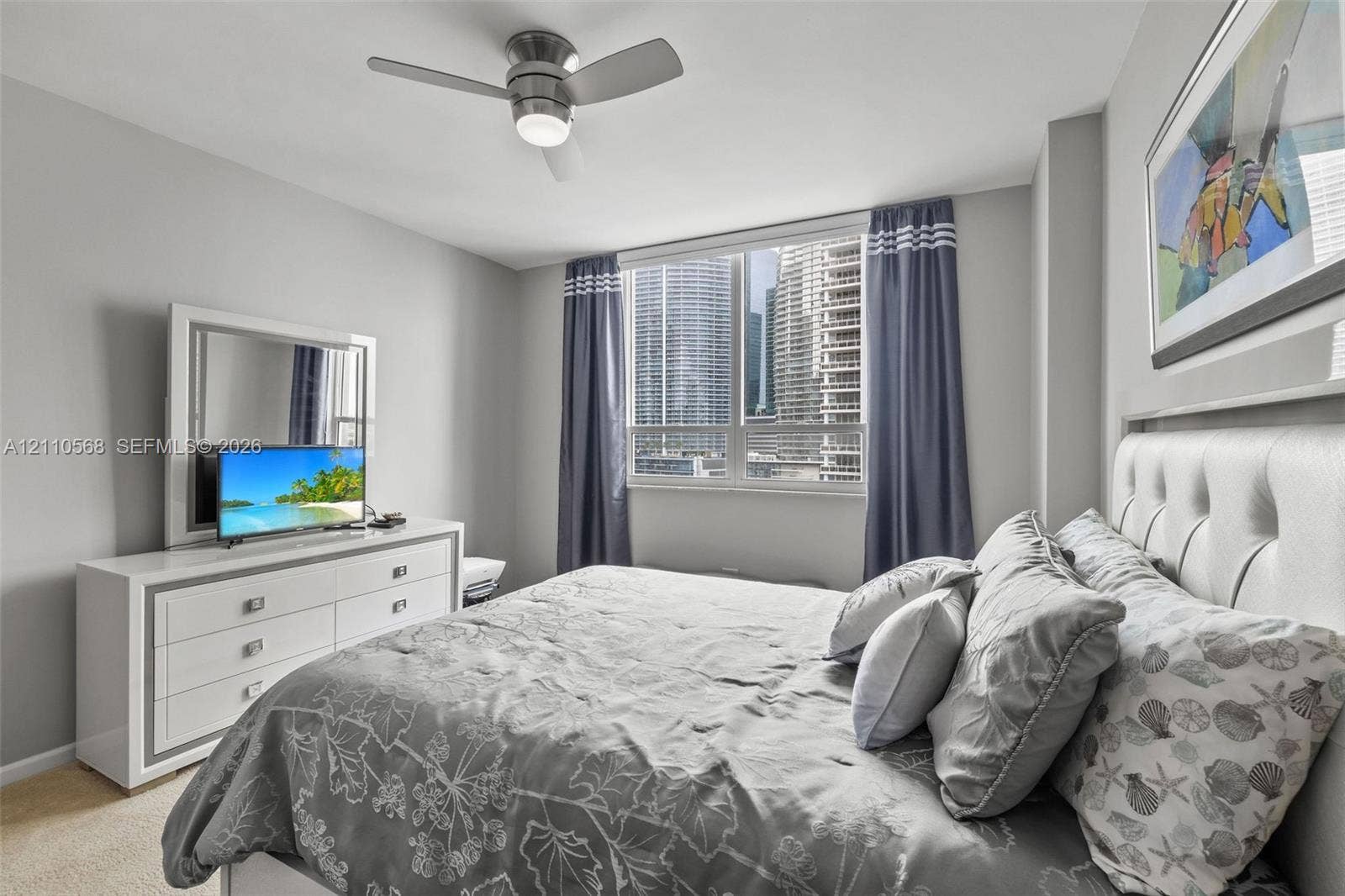 801 Brickell Key Boulevard, #2006, Miami, FL 33131 Neutral-toned interior featuring a ceiling fan with integrated lighting and a large window with urban exterior exposure