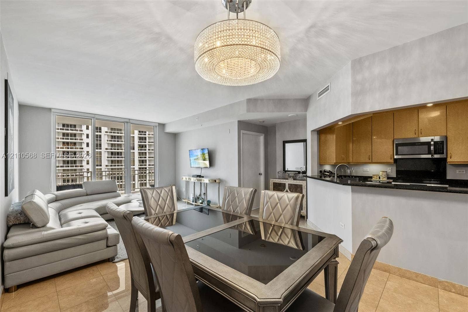 801 Brickell Key Boulevard, #2006, Miami, FL 33131 Open-concept interior featuring large-format tile flooring, a crystal drum chandelier, and expansive floor-to-ceiling windows