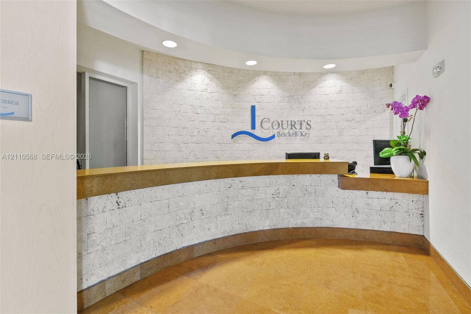 801 Brickell Key Boulevard, #2006, Miami, FL 33131 Concierge reception desk featuring a curved stone-clad counter, textured stone wall paneling, and integrated recessed lighting