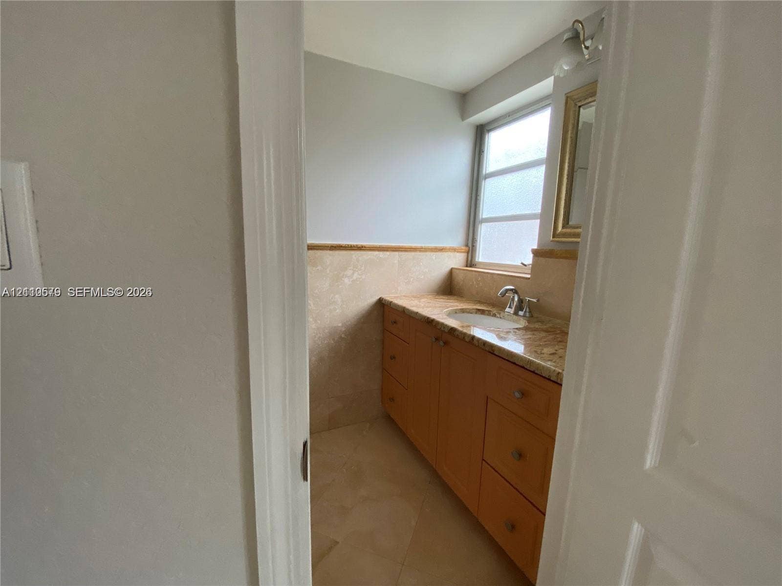 232 NE 12th Avenue, #301, Hallandale Beach, FL 33009 Bathroom featuring a wood-finish vanity with a stone countertop, an integrated sink with a chrome faucet, neutral stone wall tiling, and stone floor tiling