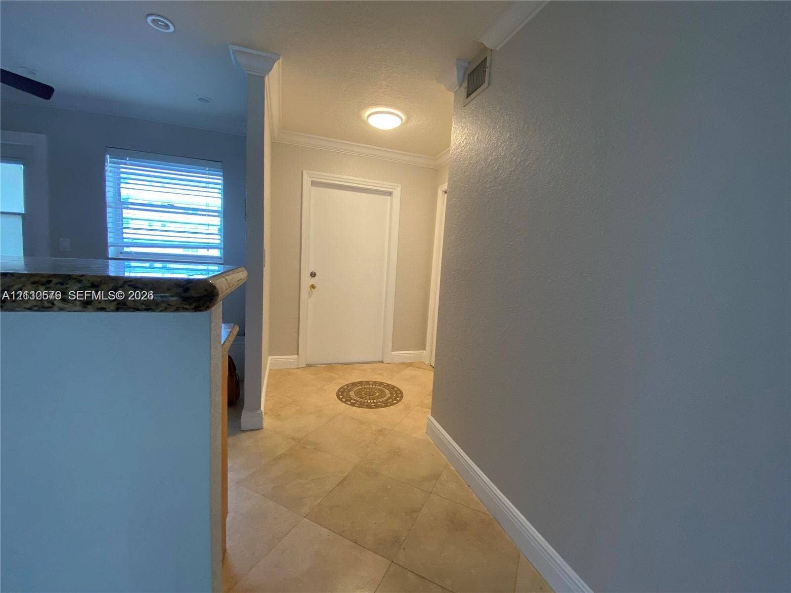 232 NE 12th Avenue, #301, Hallandale Beach, FL 33009 Entryway featuring tile flooring, crown molding, and a solid-panel door with architectural casing