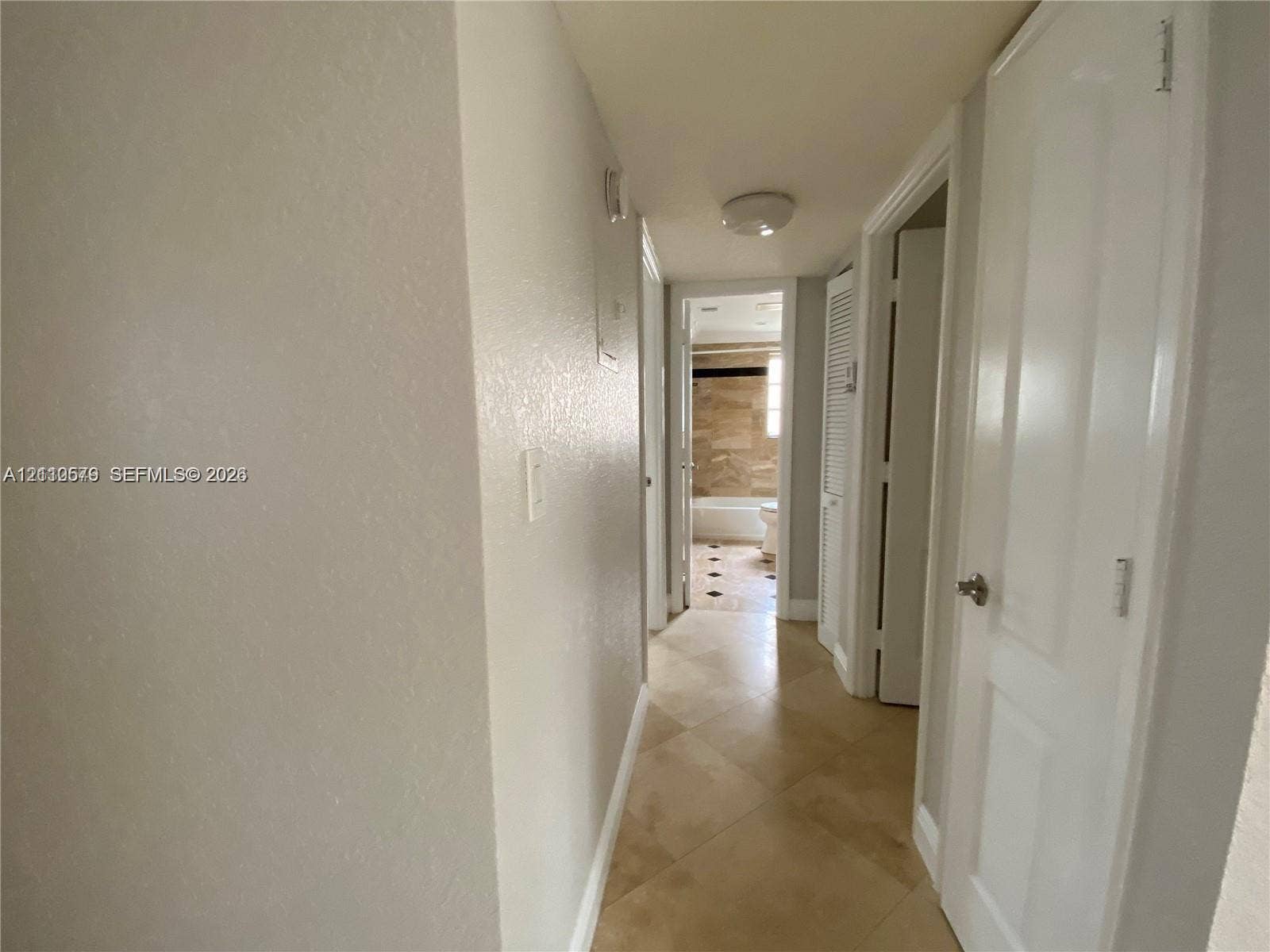 232 NE 12th Avenue, #301, Hallandale Beach, FL 33009 Hallway featuring diagonal tile flooring, smooth-finish walls, multiple panel doors, and a ceiling-mounted light fixture