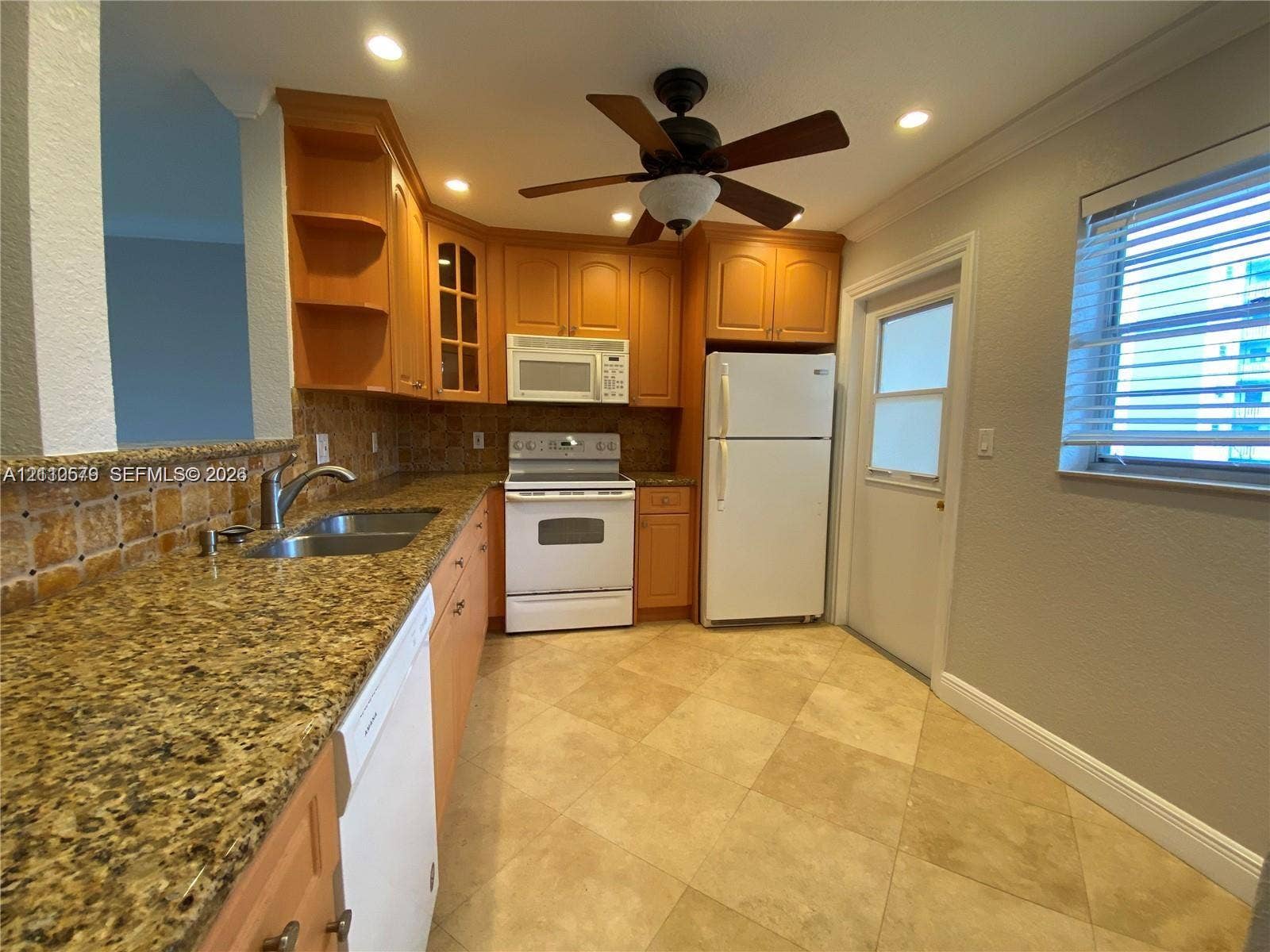 232 NE 12th Avenue, #301, Hallandale Beach, FL 33009 Kitchen featuring wood cabinetry, stone-surface countertops, stone tile backsplash, tile flooring, and integrated ceiling fan