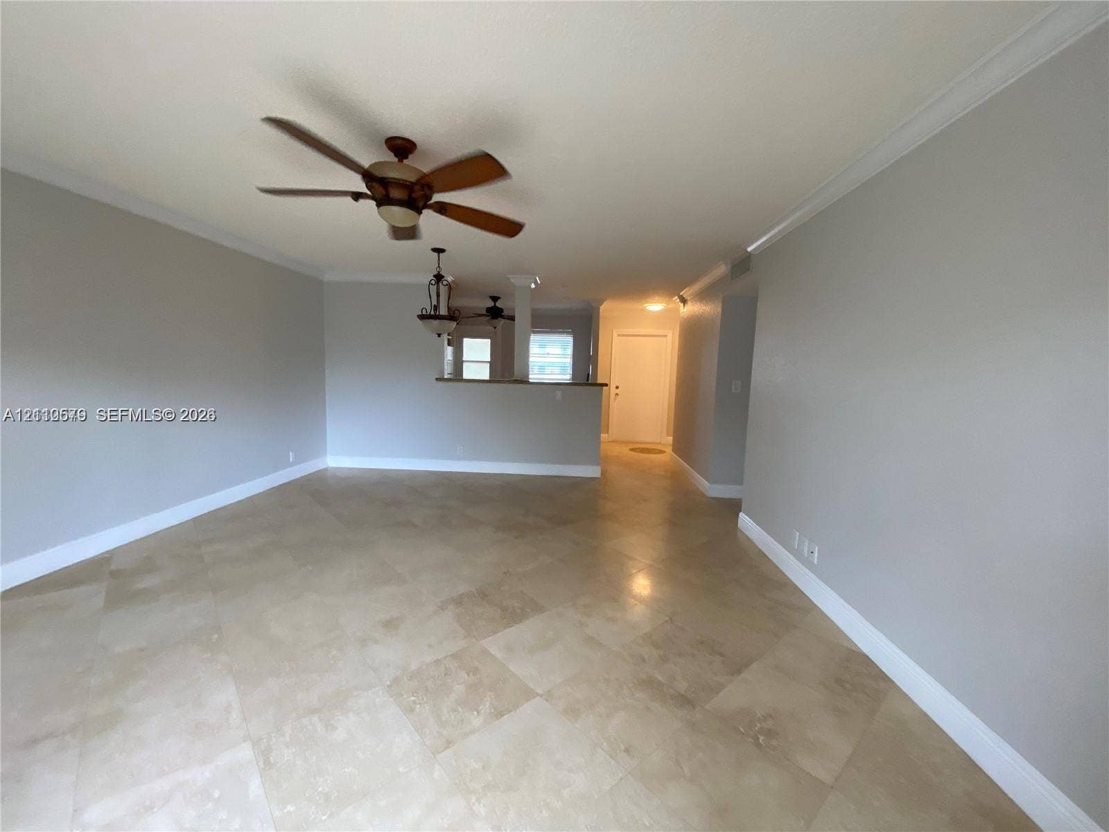 232 NE 12th Avenue, #301, Hallandale Beach, FL 33009 Interior space featuring large-format tile flooring, crown molding, a ceiling fan with integrated lighting, a partial wall partition with a counter surface, and an attached multi-light pendant fixture