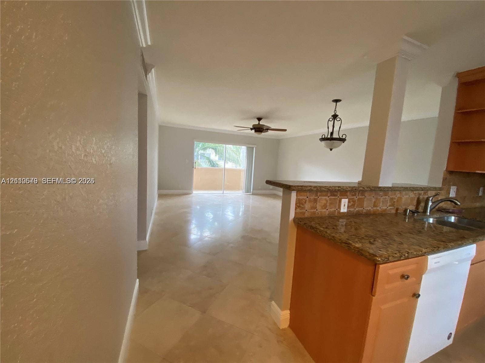 232 NE 12th Avenue, #301, Hallandale Beach, FL 33009 Open-concept interior featuring large-format tile flooring, a kitchen peninsula with stone-finish countertops, decorative tile backsplash, recessed ceiling fan, and sliding glass doors