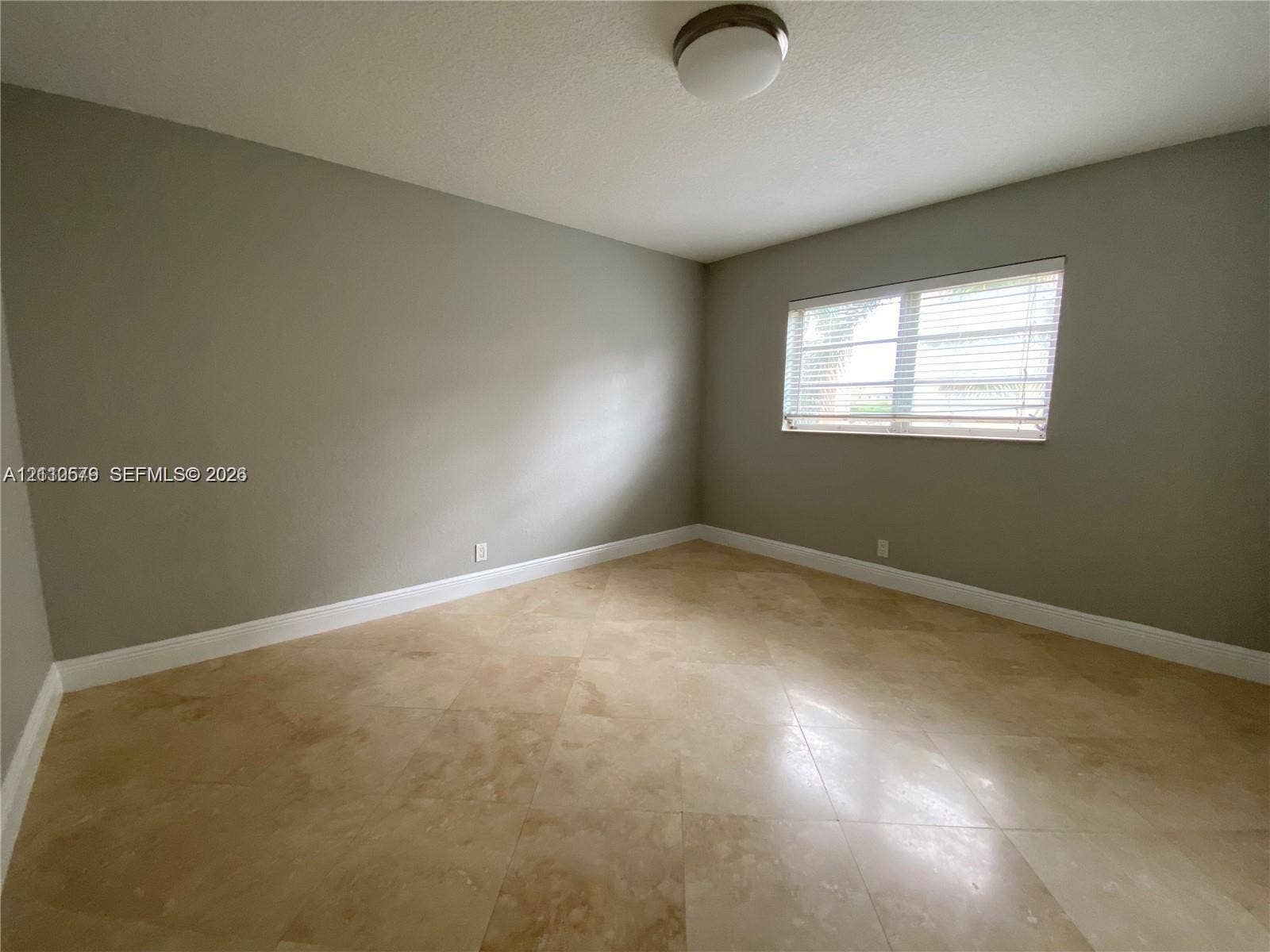232 NE 12th Avenue, #301, Hallandale Beach, FL 33009 Neutral interior space featuring stone tile flooring, a window with horizontal blinds, and a flush-mount ceiling light