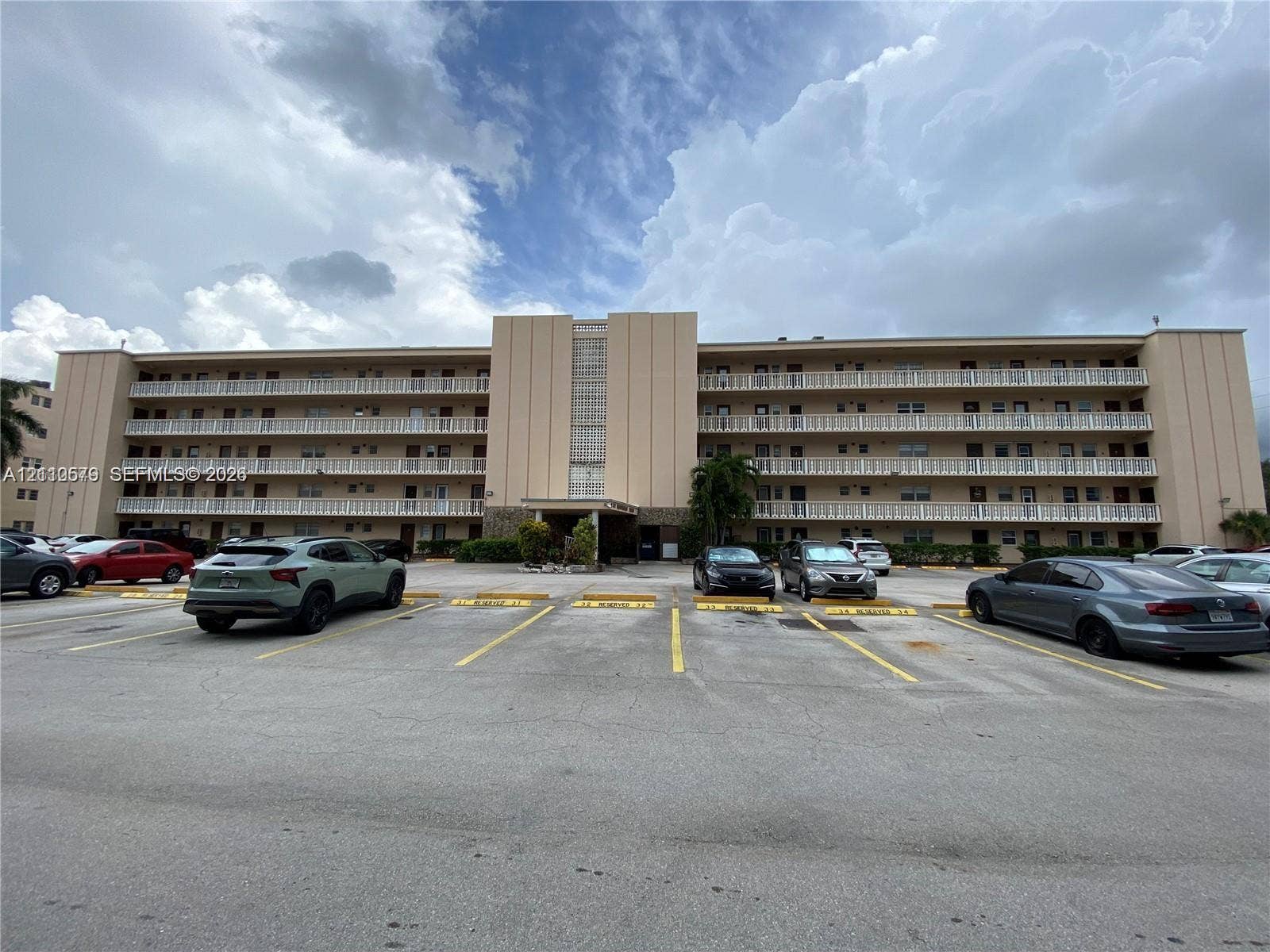 232 NE 12th Avenue, #301, Hallandale Beach, FL 33009 Multi-story residential building exterior featuring a textured facade, stacked open-air balconies, and a central glass block accent column