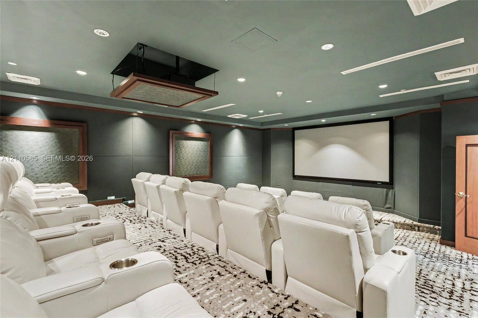 600 W Las Olas Boulevard, #202S, Fort Lauderdale, FL 33312 Media room featuring a fixed projection screen, ceiling-mounted projector, tiered floor levels, recessed lighting, and integrated wall paneling