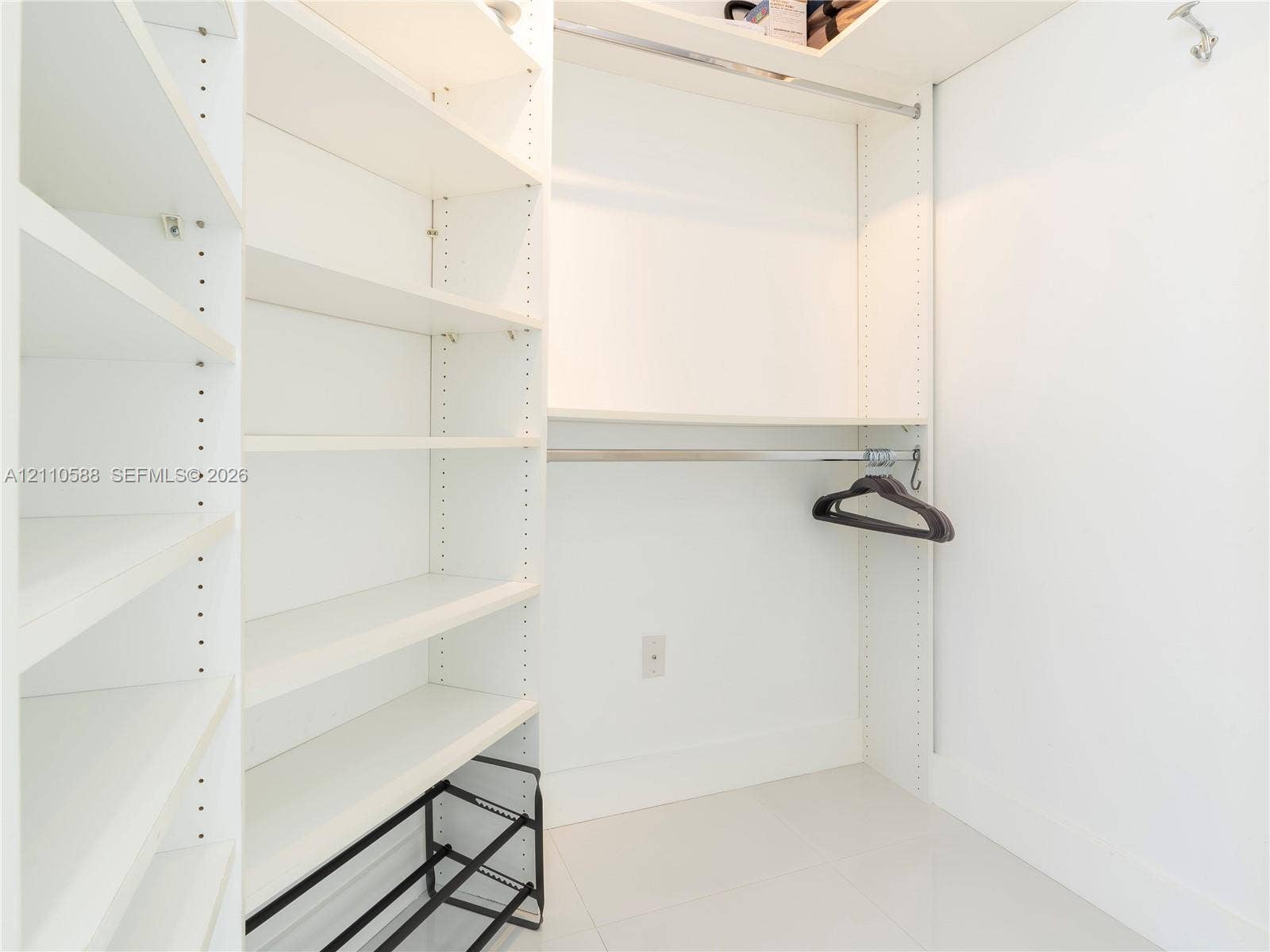 Custom closet organization system featuring adjustable white shelving, hanging rods, and an integrated tiered shoe rack
