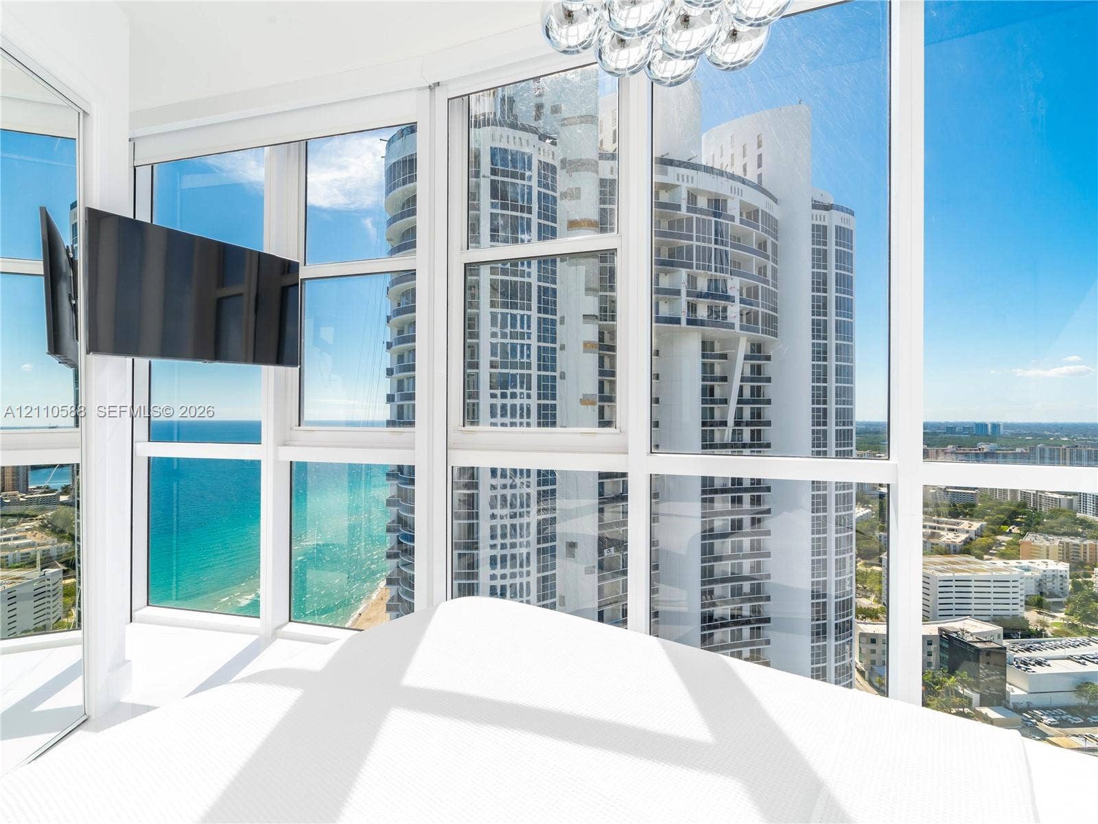 Floor-to-ceiling glass walls, multi-panel windows, and a spherical multi-bulb pendant fixture