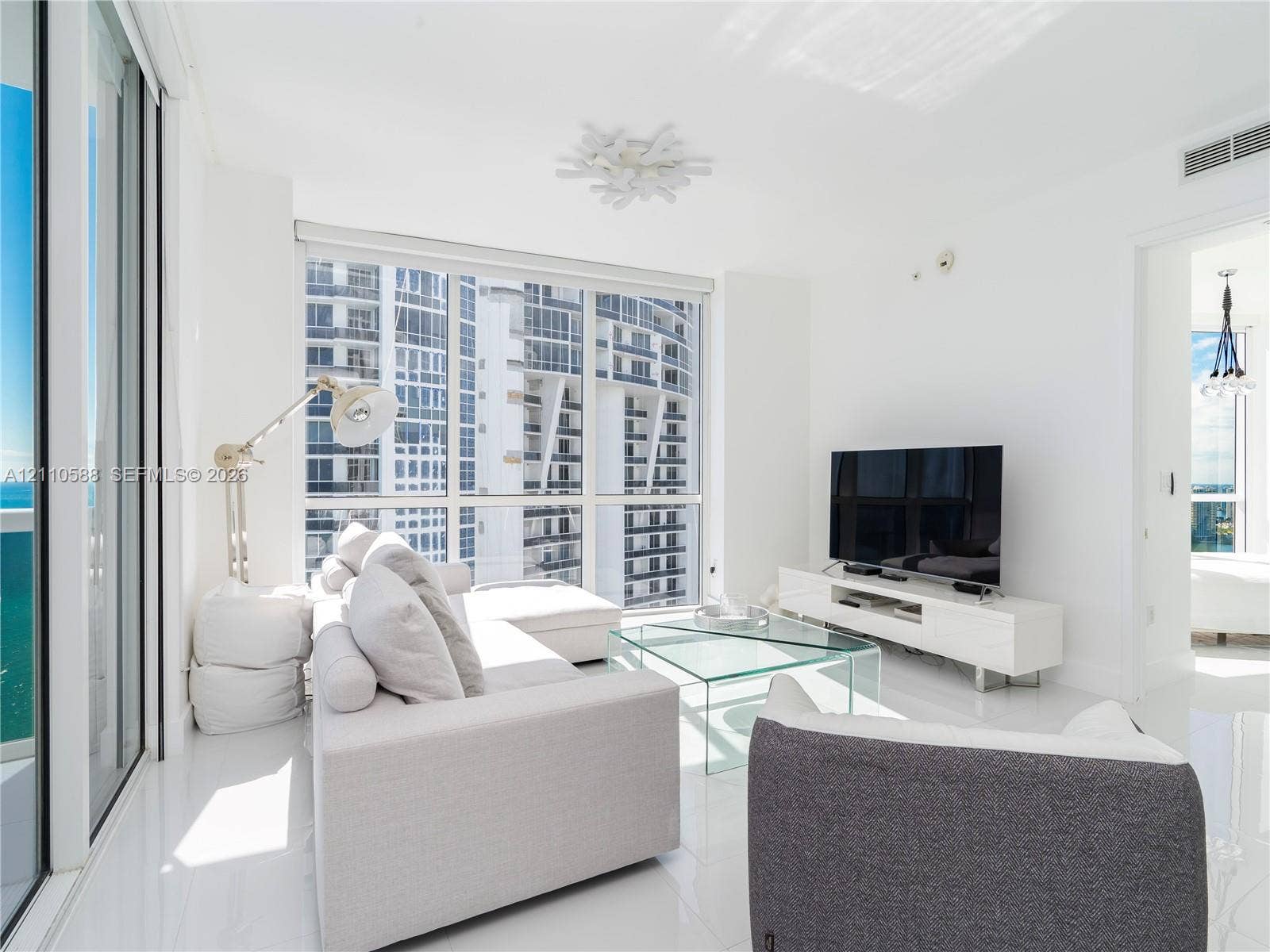 Floor-to-ceiling windows, high-gloss white flooring, white walls, and a decorative contemporary ceiling fixture