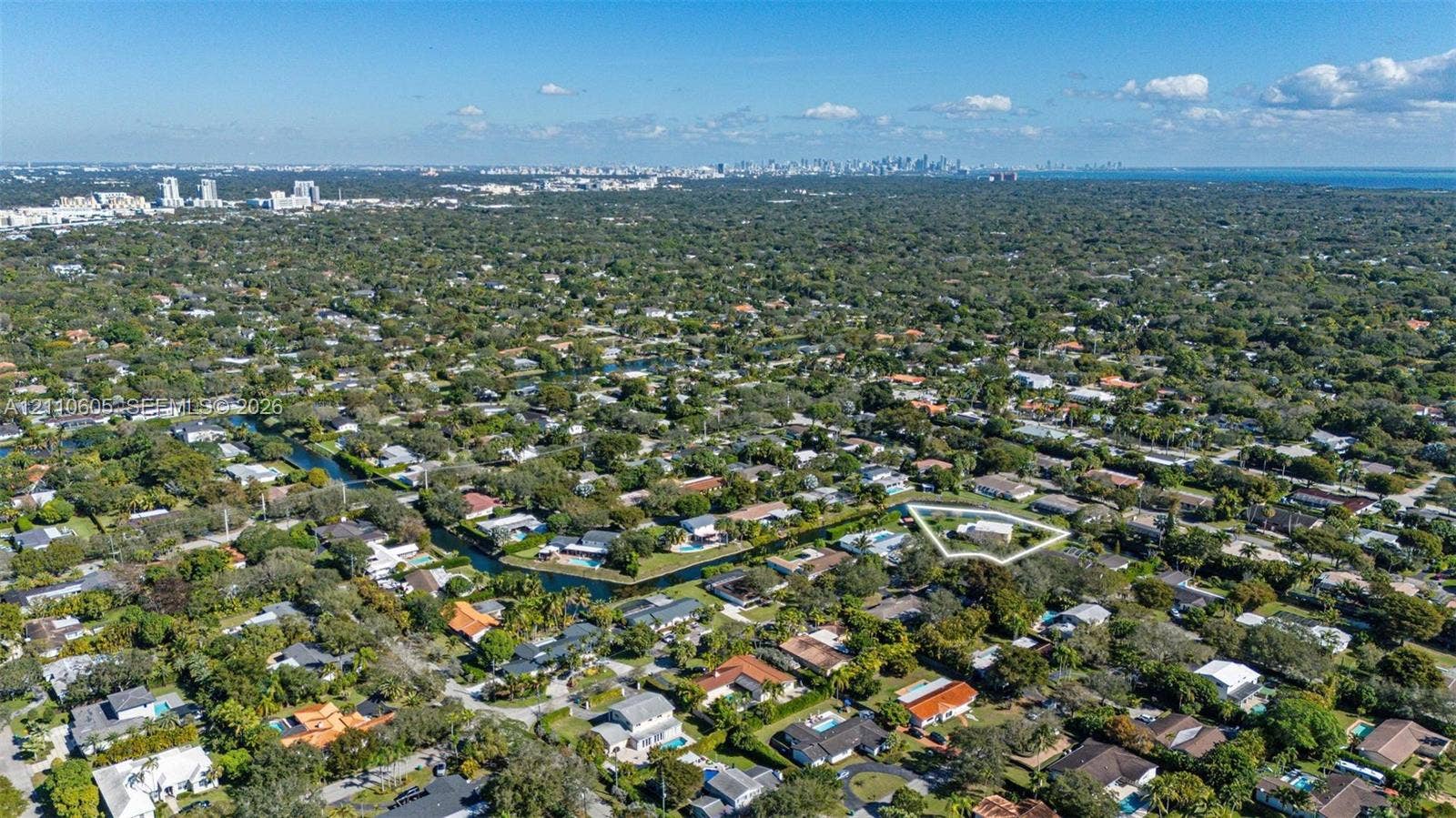 Aerial perspective of a residential property featuring a large lot, perimeter landscaping, and proximity to a canal