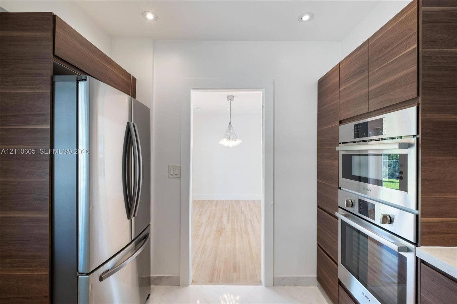 Kitchen featuring full-height wood-finish cabinetry, stainless steel French-door refrigerator, built-in stainless steel double wall ovens, and recessed ceiling lighting