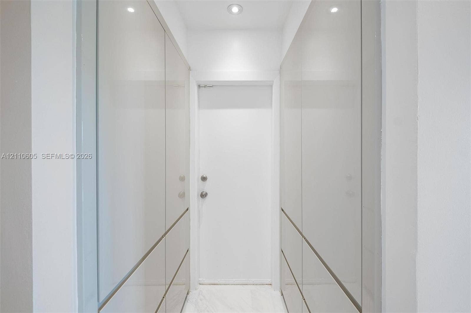 Floor-to-ceiling high-gloss cabinetry with integrated hardware, recessed ceiling lighting, and stone-finish flooring