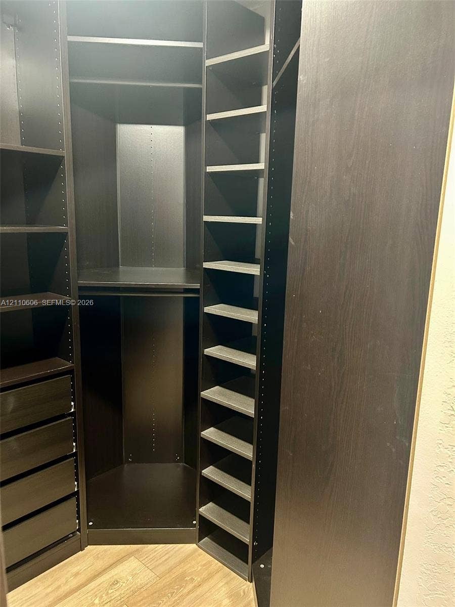 Custom built-in closet organization system featuring dark wood-finish cabinetry, floor-to-ceiling adjustable shelving, multi-tiered hanging rods, and integrated soft-close drawer storage