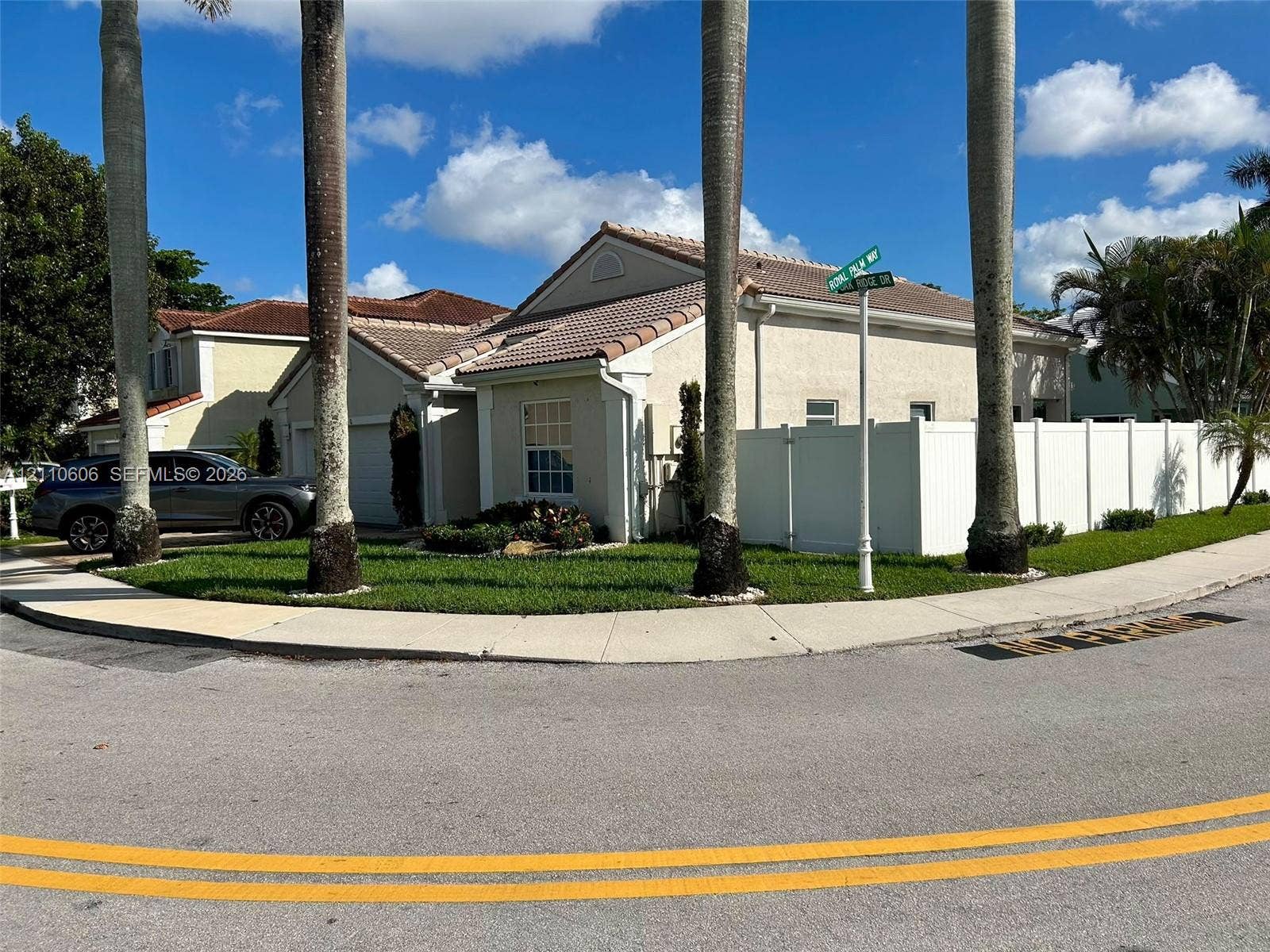 Single-story residence featuring a tile roof, stucco exterior, corner lot positioning, and white privacy fencing