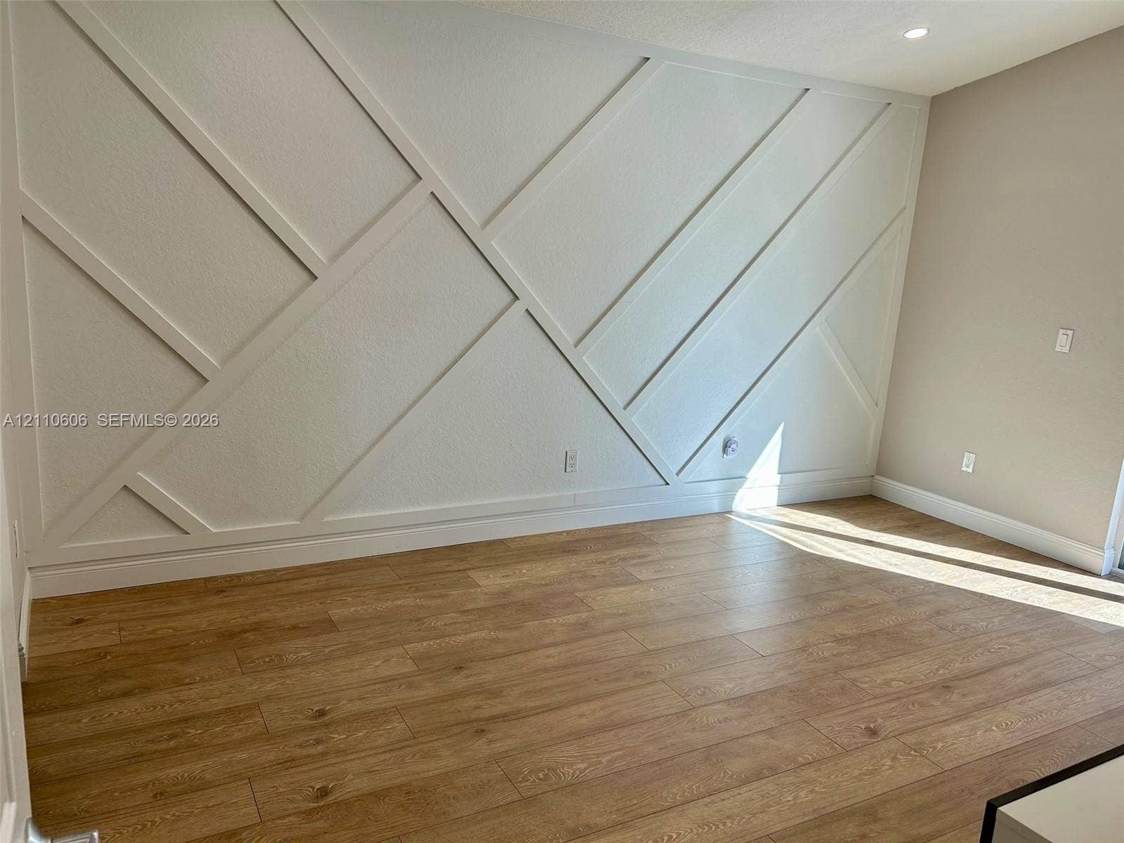 Accent wall featuring geometric millwork and wood-finish flooring