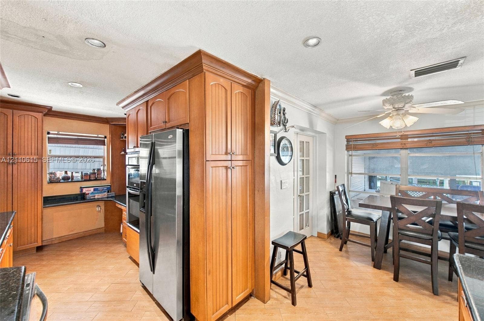 Kitchen featuring wood-finish cabinetry, stainless steel appliances, recessed ceiling lighting, tile flooring, and a glass-paned door