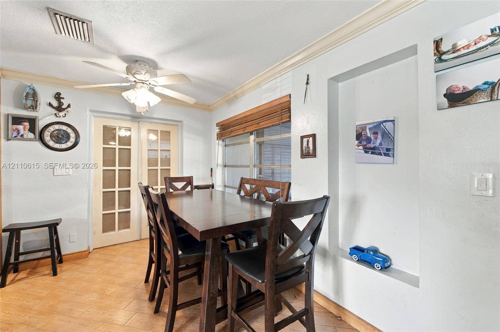 Interior space featuring tile flooring, crown molding, built-in wall niche, ceiling fan with light fixture, and glass-paneled double doors