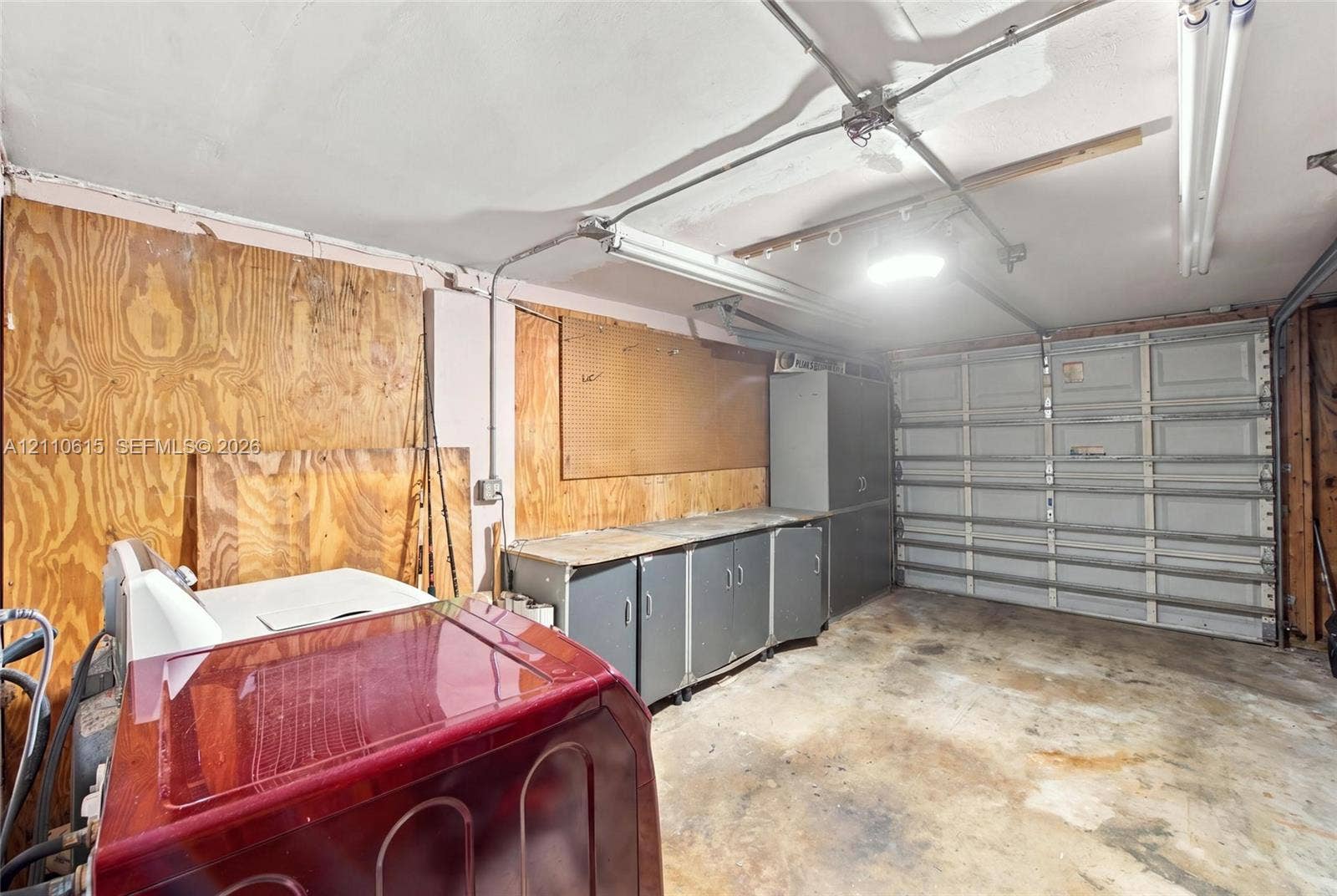 Garage space featuring plywood wall paneling, built-in metal cabinetry, and a sectional overhead garage door