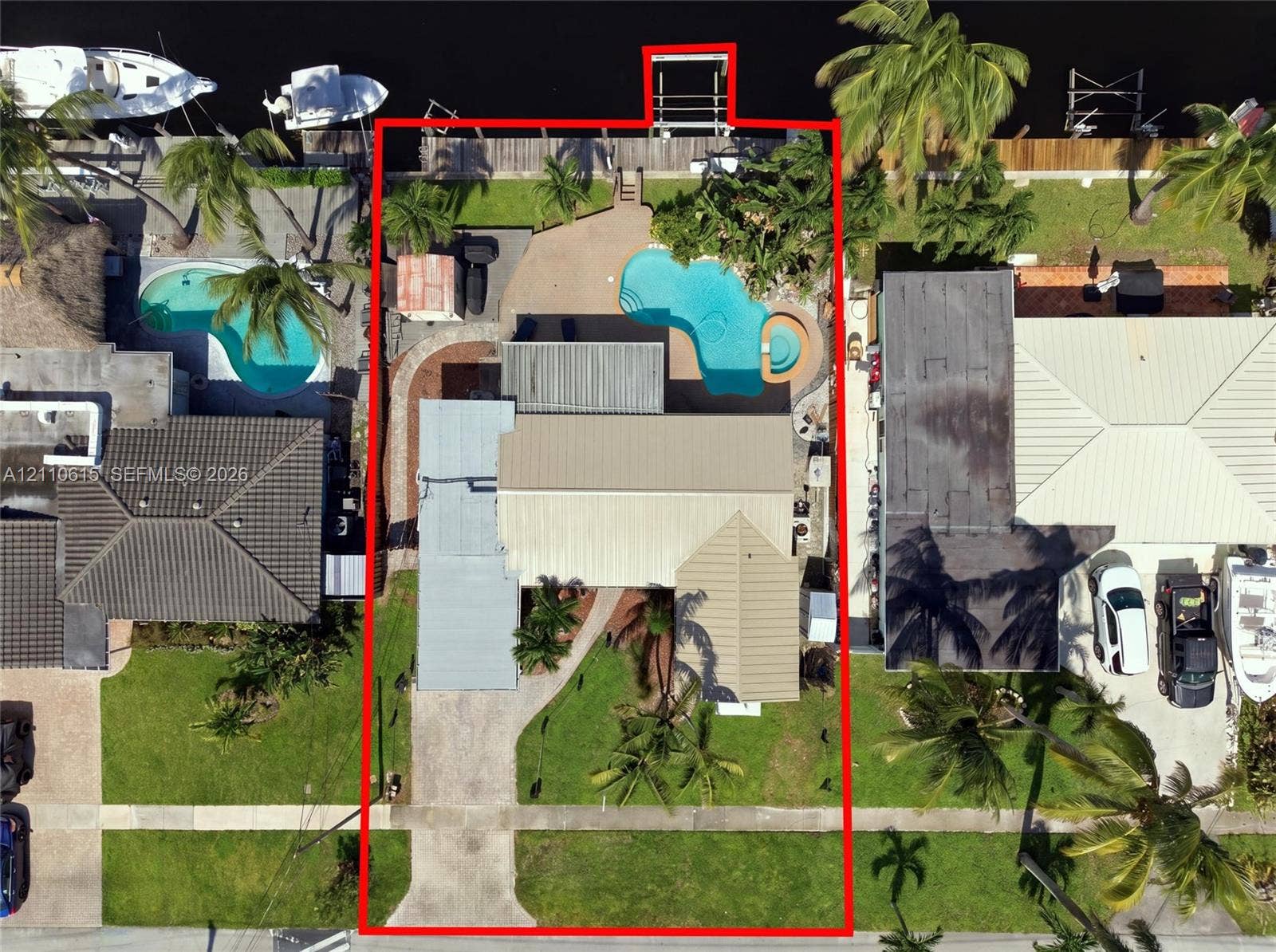 Waterfront property featuring a private boat dock, in-ground swimming pool with integrated spa, concrete patio, and a concrete driveway