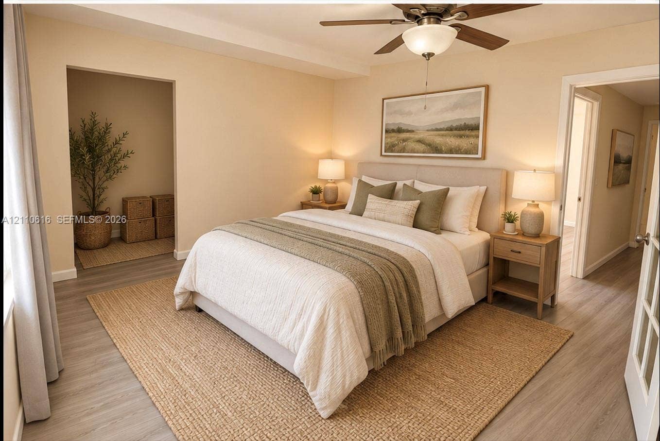 Neutral-toned bedroom featuring wood-finish flooring, a recessed nook, and a ceiling fan with integrated lighting