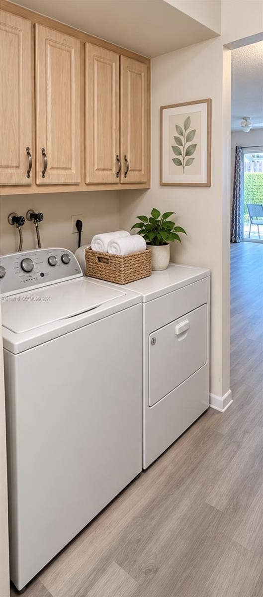 Laundry space featuring light-toned cabinetry, wood-finish flooring, and wall-mounted plumbing hookups
